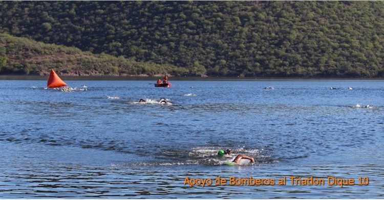 Triatlón Dique 10: nadadores cruzando la 2da boya. Al fondo bomberos atentos en una lancha